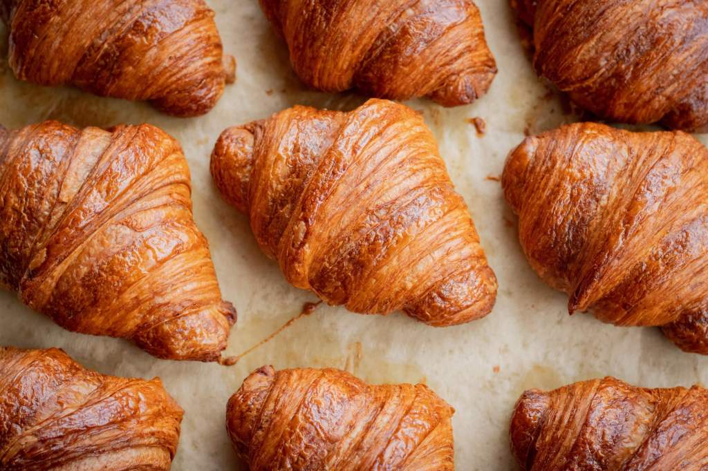 Croissants on a baking tray with while baking sheet 